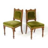 A pair of late 19thC / early 20thC oak chairs with pointed cresting rail and uprights having floral