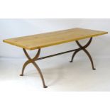 A late 20thC pine topped dining table with a wrought iron X-framed base having a central trestle