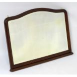 A 20thC mahogany mantle mirror with bevelled edge, shaped top and a stepped base.