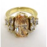 A gilt metal dress / cocktail ring set with amber coloured facet cut central stone flanked by white