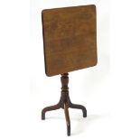 A late 18thC / early 19thC mahogany square tilt top table with an elegantly turned stem above three