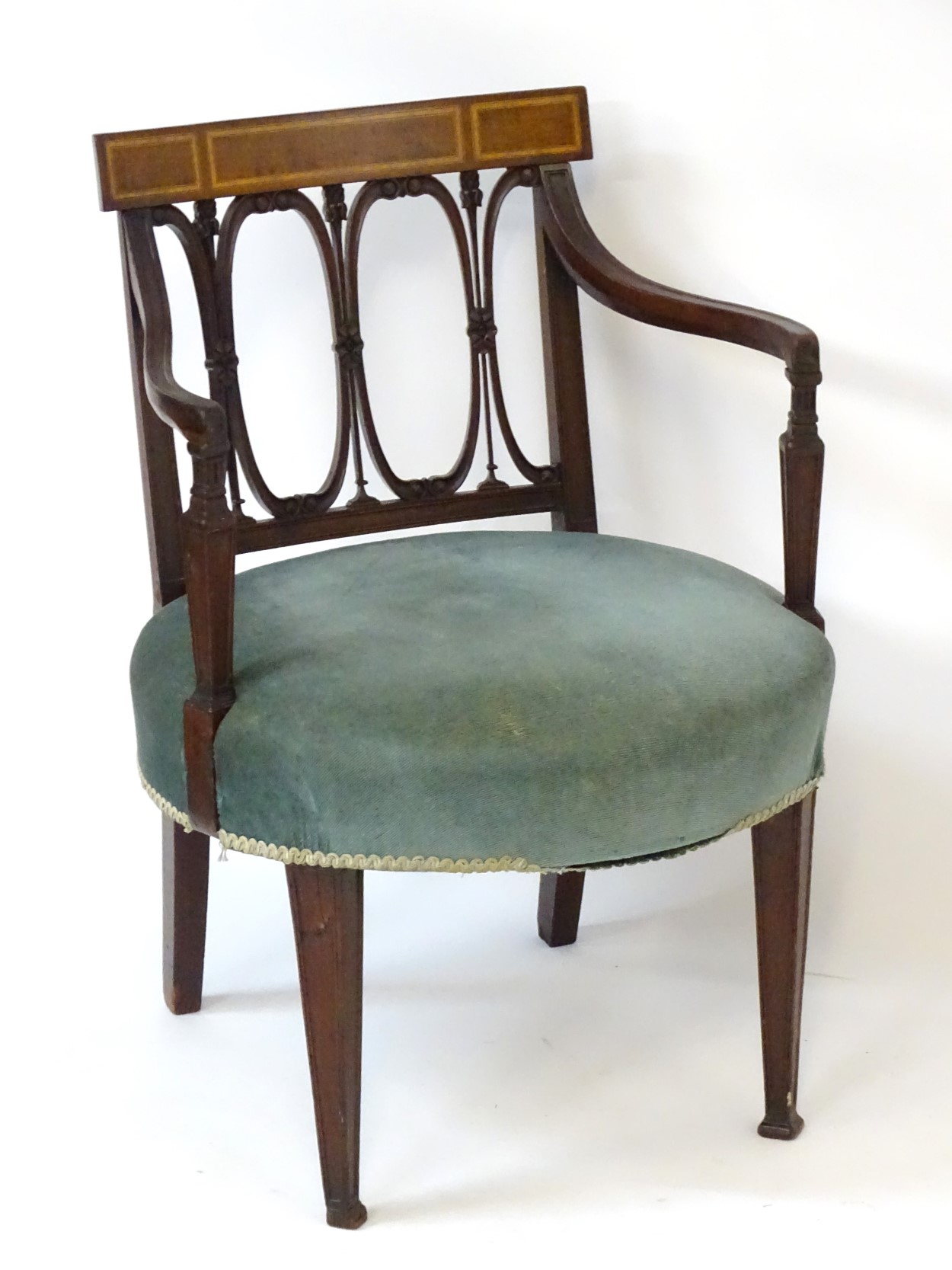 An Edwardian mahogany open armchair with satinwood inlaid top rail, repeating carved oval backrest,