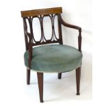 An Edwardian mahogany open armchair with satinwood inlaid top rail, repeating carved oval backrest,