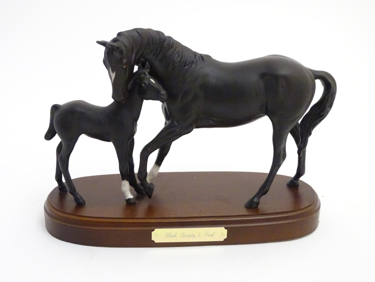 A Royal Doulton 'Black Beauty and Foal' equestrian group on a wooden plinth. Approx.