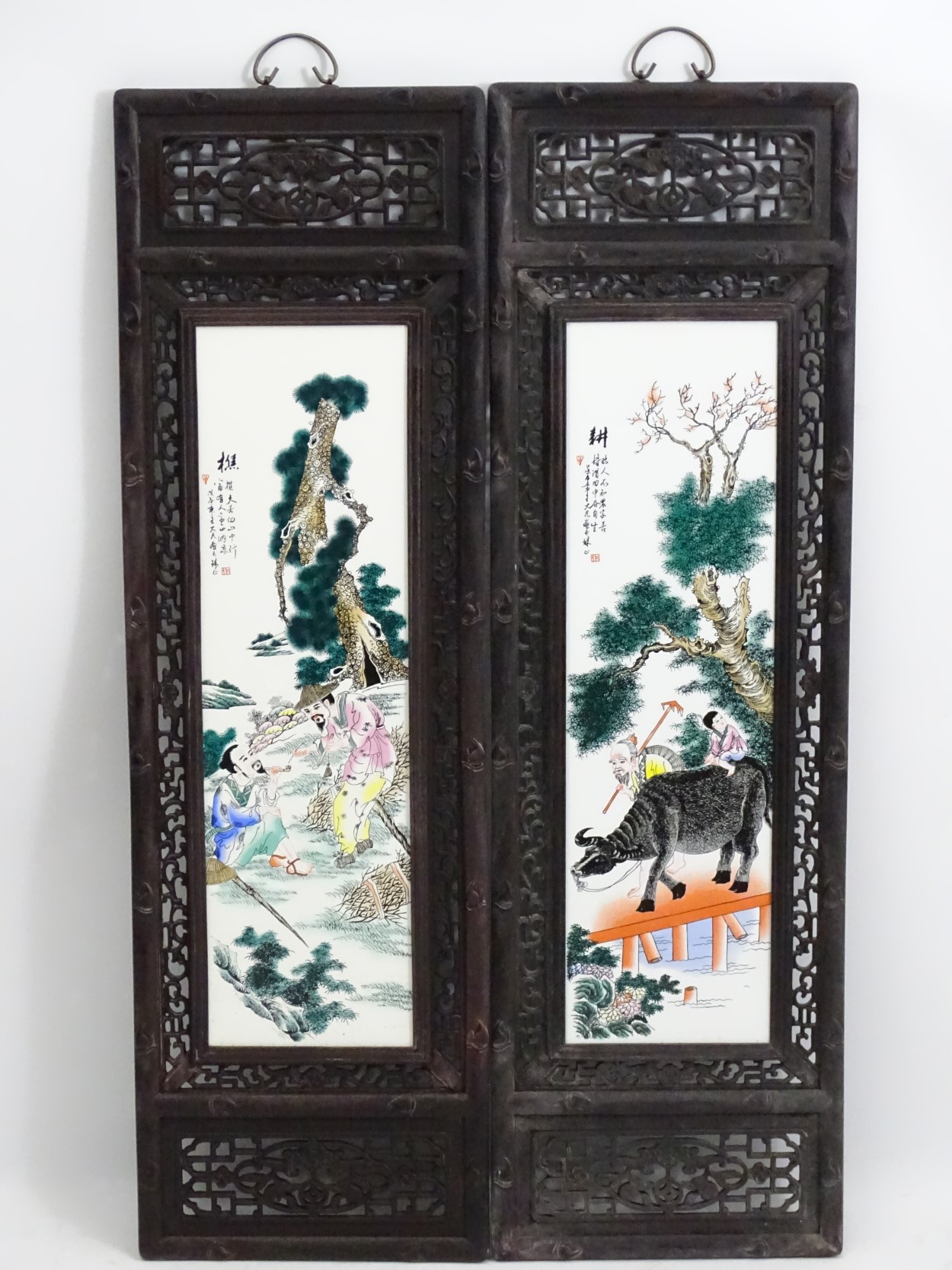 A pair of Chinese hardwood screens each with openwork decoration and an inlaid Chinese ceramic