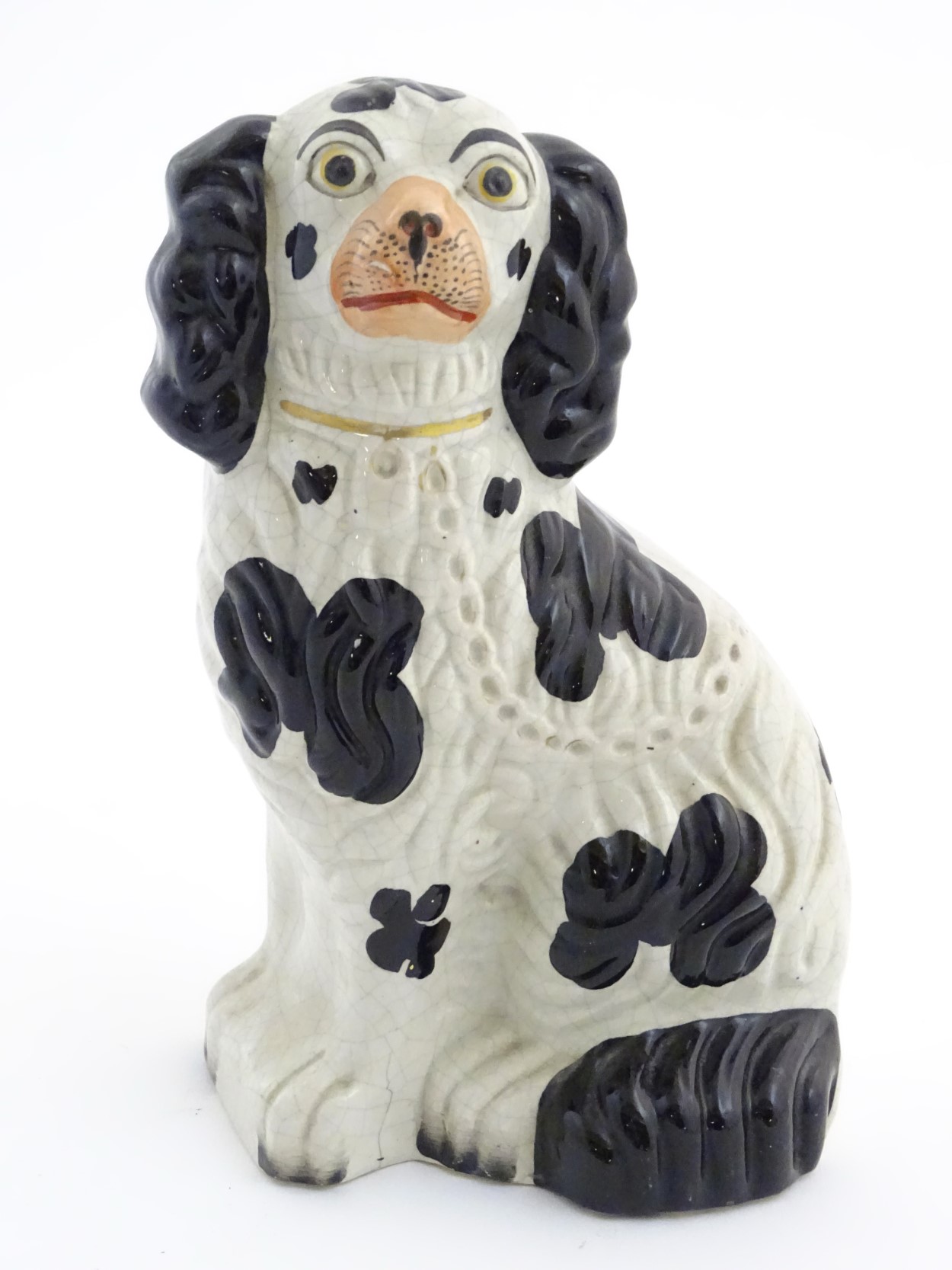 A Victorian Staffordshire seated spaniel with black patch decoration and gilt lock and chain detail.