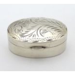 A silver pill box of ovoid form with engraved decoration.