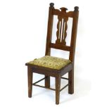 An early 20thC childs chair with pierced back splat above a squared upholstered seat,