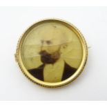 A 15ct gold and gilt metal brooch of circular form with gold portrait photograph to centre.