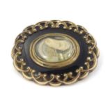 Mourning / Memorial jewellery: A 19thC yellow metal brooch with black enamel detail and central