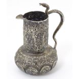 A small white metal jug with floral and foliate decoration and snake formed handle. Probably Indian.