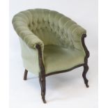 A late 19thC / early 20thC deep buttoned barrel back chair, with scrolled carved show wood frame,