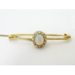 A gold bar brooch set with central opal bordered by pearls 1 ¾” wide CONDITION: