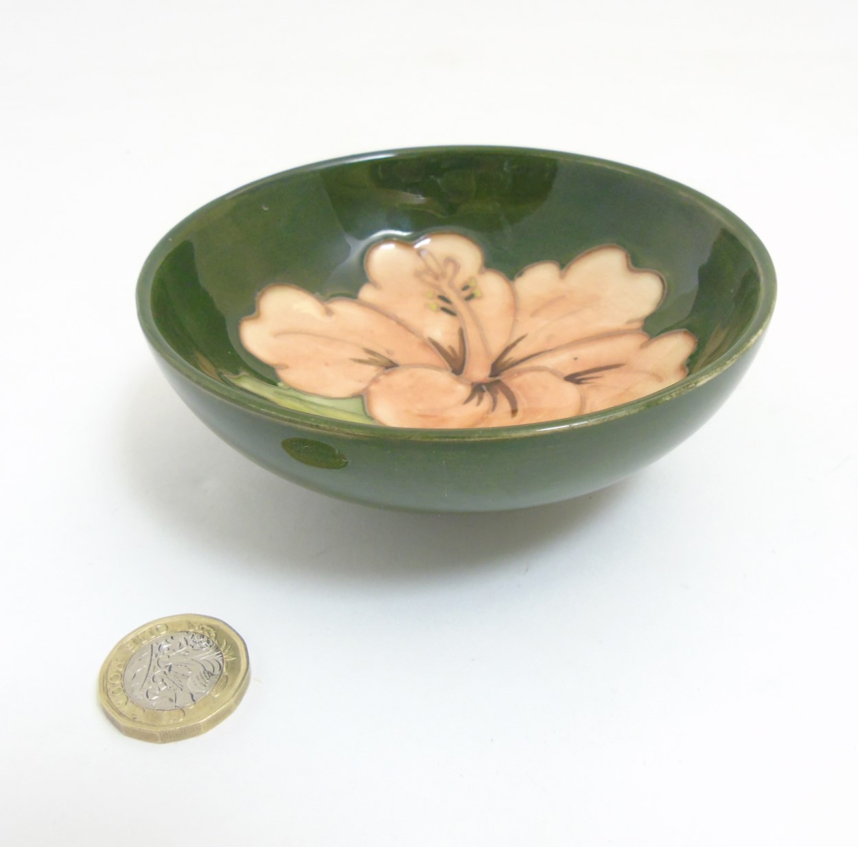 A Moorcroft Hibiscus pottery bowl dish, with pink hibiscus design on green ground,