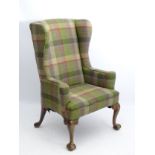 An 18thC wingback armchair with tartan upholstery and swept arms,