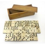 A set of ebony and bone dominoes in a wooden box with a sliding lid. Approx.