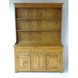 A rustic pine dresser with moulded cornice above a three tier plate rack,