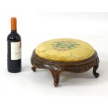 A Victorian mahogany footstool of circular form with drop in seat and carved floral frame.
