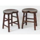 A pair of early 20thC mahogany stools with heart shaped saddle seats,