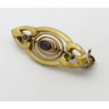 A yellow metal brooch set with red green and purple stones.