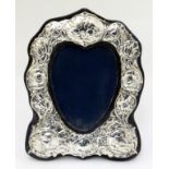 A heart shaped photograph frame with silver surround having embossed cherub / angel decoration .