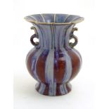 A twin handled Chinese high-fired, flambe globular vase with a splayed foot and flared rim.