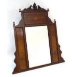 A late 19thC / early 20thC mahogany mirror with carved floral pediment flanked by urn finials.
