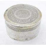 A white metal lidded pot with engraved decoration and script to top.