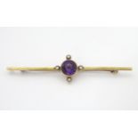 A late 19thC / early 20thC 15ct gold bar brooch set with central amethyst and four seed pearls.