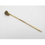 A gilt metal stick pin surmounted by gold nugget style decoration.