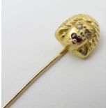 A gold stick pin with head of a figure to top set with diamonds and rubies.