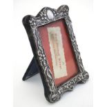 A photograph frame with silver surround having embossed decoration.