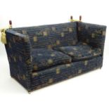 A 20thC Knowle sofa with blue upholstery and latin script having turned wooden finials to secure