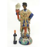 A tall South American ceramic figure wearing colourful robes and holding a roundel decorated with a
