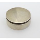A silver pill box of circular form with hinged lid.