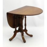 An early 20thC walnut Sutherland table with central column surrounded by four turned supports,