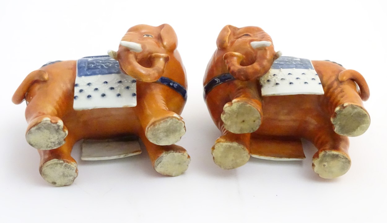 A pair of Chinese ceramic elephants with rust coloured bodies and blue and white patterned saddles. - Image 7 of 7