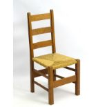 An early 20thC oak Heals Letchworth chair with envelope rush seat and ladder back,
