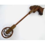 A mid to late 20thC carved wooden hobby horse on two wheels, with handle. Approx. 42 1/2" high.