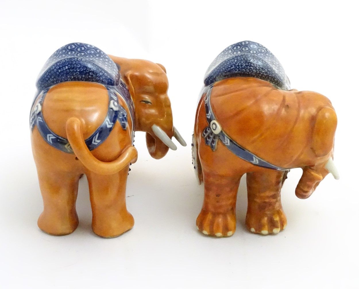 A pair of Chinese ceramic elephants with rust coloured bodies and blue and white patterned saddles. - Image 5 of 7