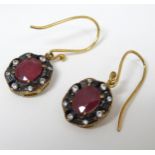 A pair of gold and gilt metal drop earrings set with red semi precious facet cut central stones