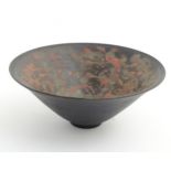 An Oriental ceramic conical shaped bowl with red and grey on black decoration.