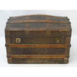 A c.1900 canvas banded semi - domed trunk opening to reveal paper lined interior.