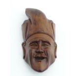 An Indonesian carved wooden wall hanging mask with hat. Bears old label verso.
