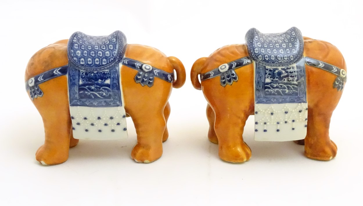 A pair of Chinese ceramic elephants with rust coloured bodies and blue and white patterned saddles. - Image 4 of 7