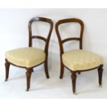A pair of early 20thC mahogany balloon back chairs with incised decoration and standing on tapering