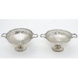 A pair of pedestal bon bon dishes with pierced decoration and twin handles.