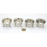 A set of 4 silver salts each with three legs and flared rims.