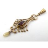 A 10k gold pendant set with purple paste stone and mother of pearl drop.