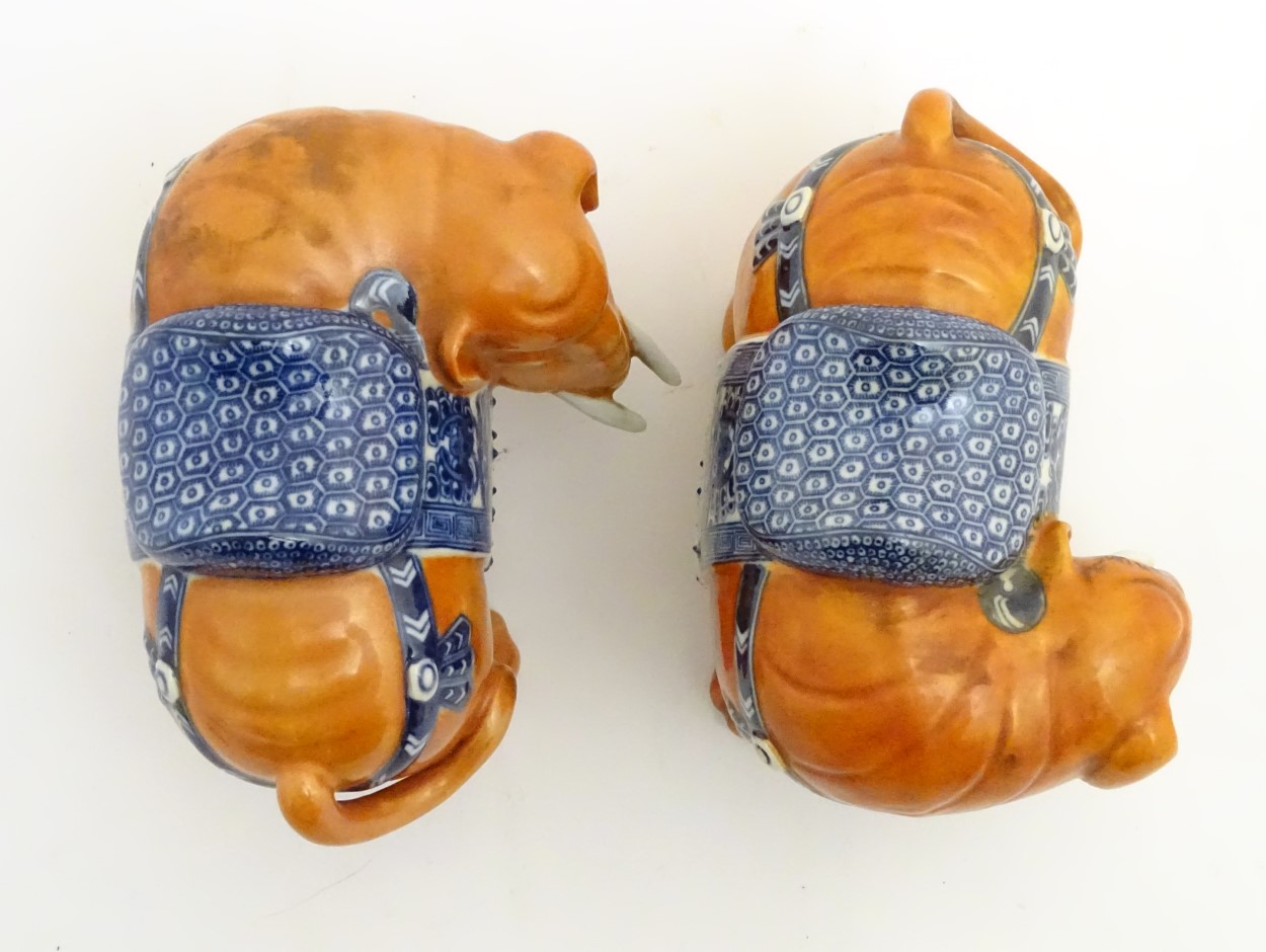 A pair of Chinese ceramic elephants with rust coloured bodies and blue and white patterned saddles. - Image 6 of 7